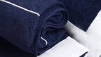 Navy and white towels with piping detail on a dark surface