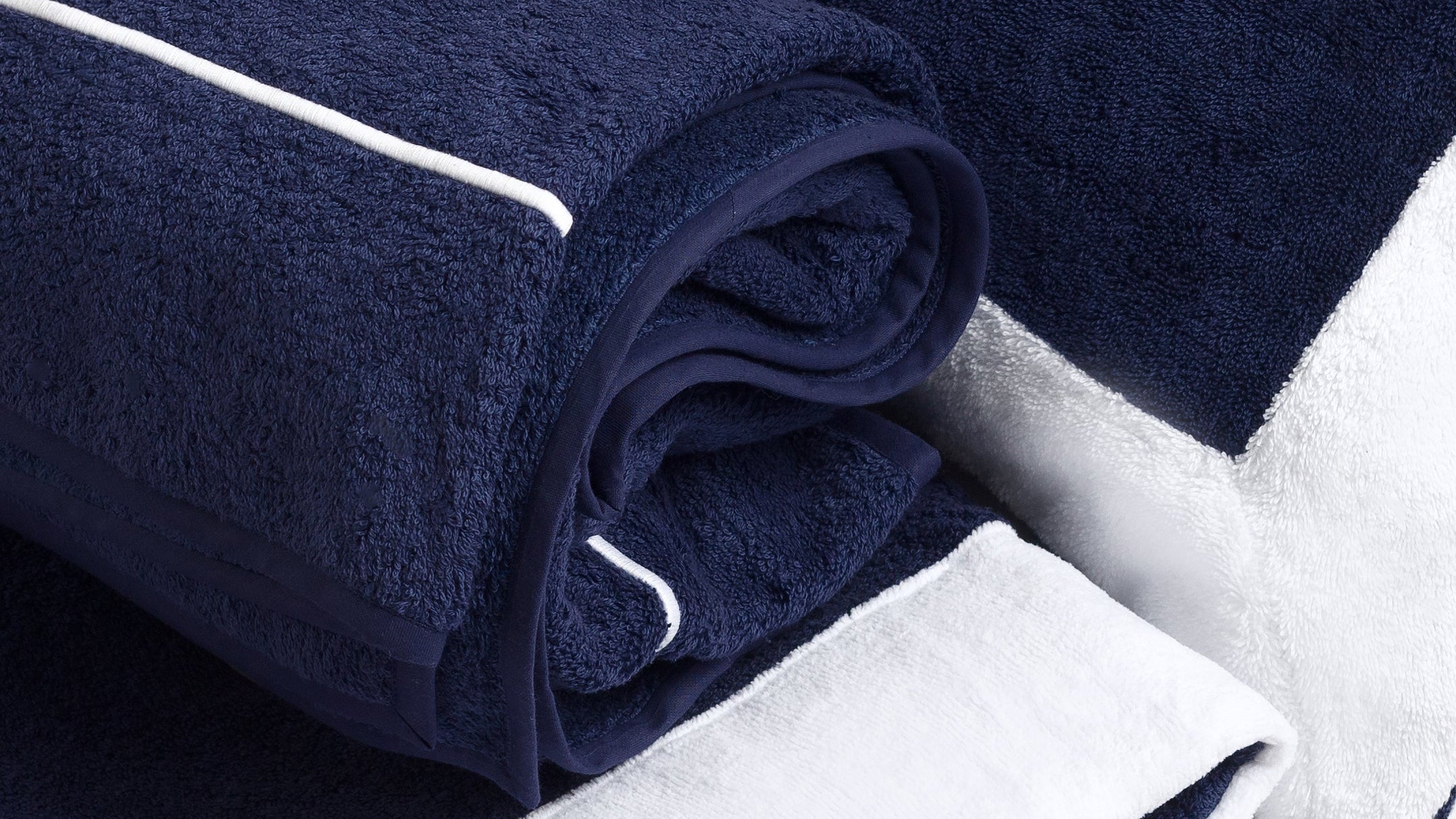 Navy and white towels with piping detail on a dark surface