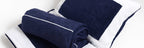 A set of folded bath towels in navy and white colors with embroidered detailing on the white towels.