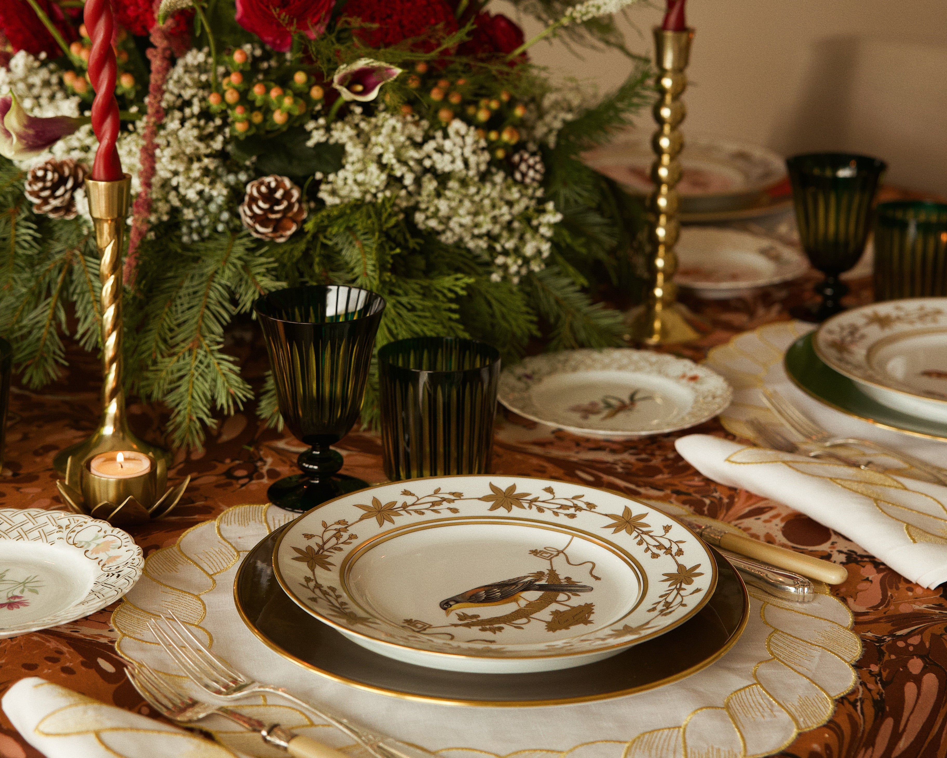 Decorative table setting with floral arrangement, candles, and patterned plates.