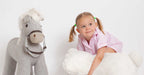 Child playing with a stuffed horse and a large white teddy bear on a white background