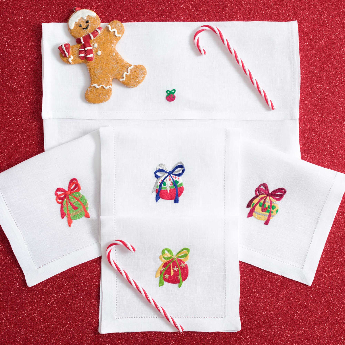 Close-up of embroidered Christmas baubles on white linen cocktail napkin