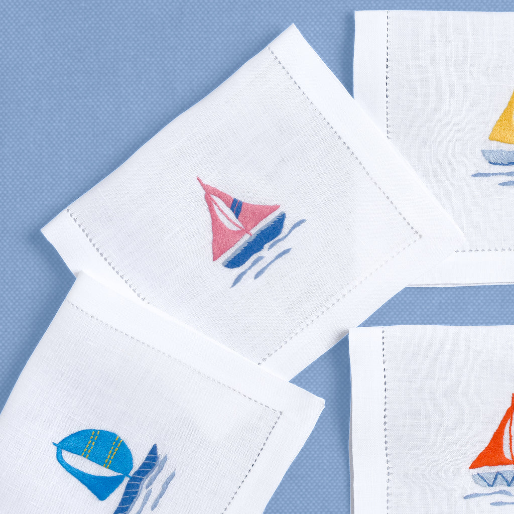 Close-up of embroidered sailboats on white linen cocktail napkin