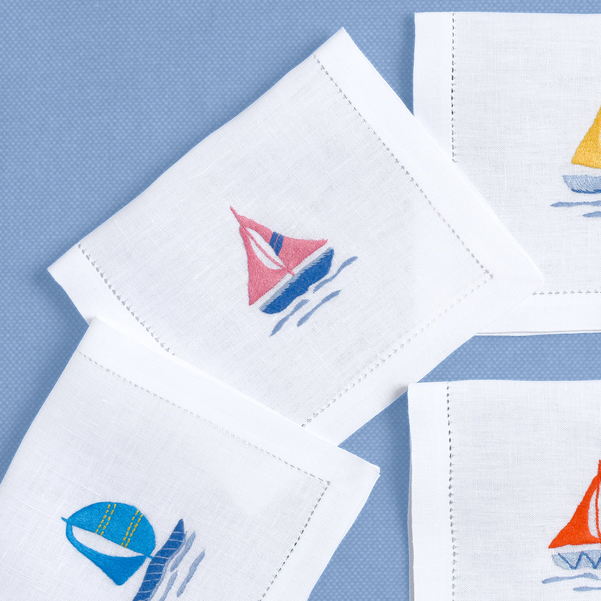 Close-up of embroidered sailboats on white linen cocktail napkin