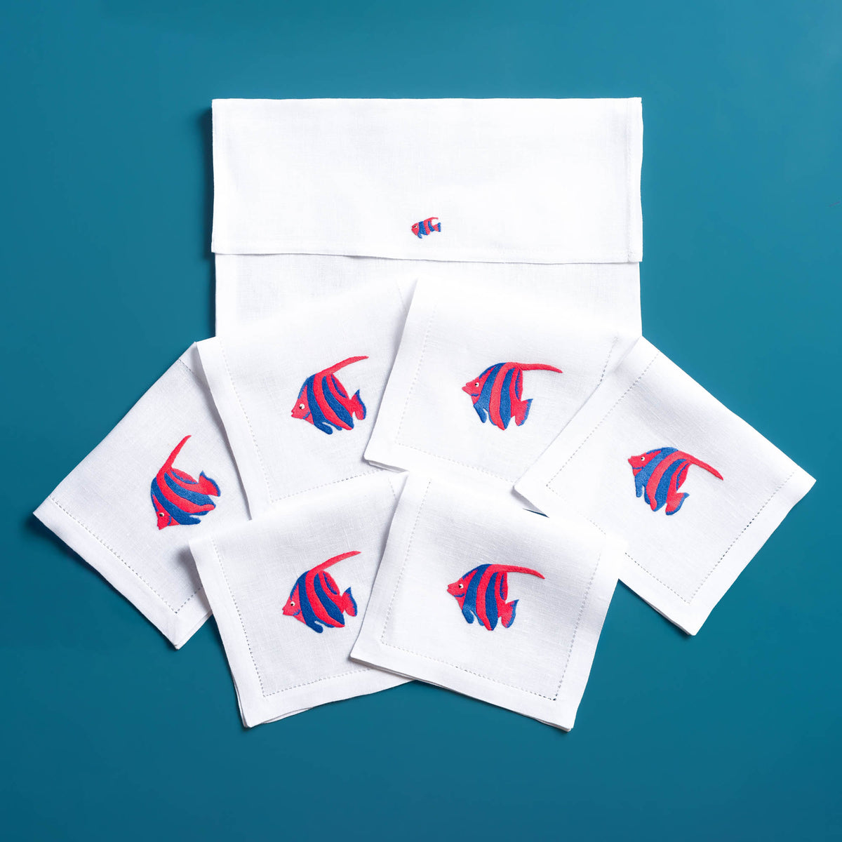 Close-up of embroidered exotic fish on white linen cocktail napkin