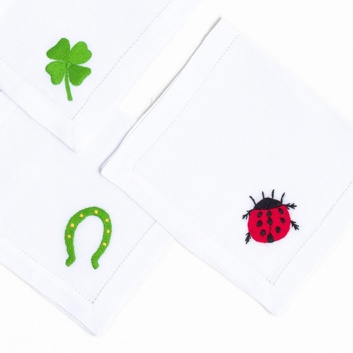 Lucky Charms embroidered good-luck motif on white linen cocktail napkin