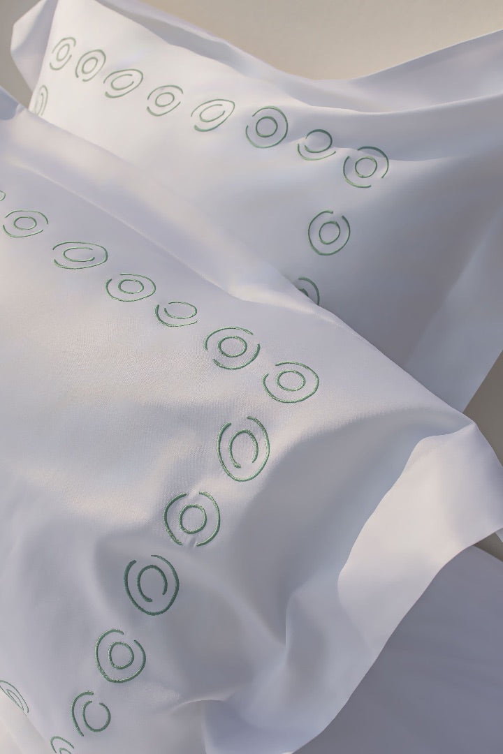 Maison Alia luxury bedding - green oval hand-embroidery pattern on white premium linen, artisan craftsmanship detail