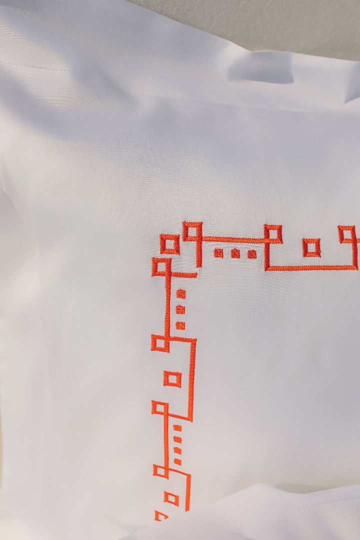 Maison Alia luxury bedding - red geometric hand-embroidery detail on white premium linen, artisan craftsmanship