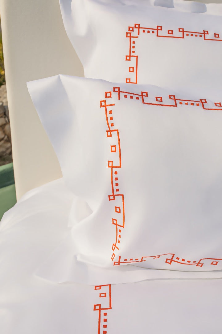 Maison Alia luxury bedding - red geometric embroidery pattern on white linen pillow, premium bed set detail