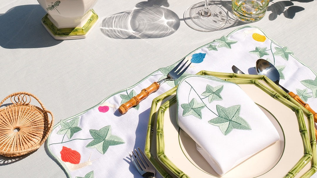Maison Alia luxury tableware 2026 - hand-embroidered ivy napkin on bamboo plate, outdoor fine dining tablescape