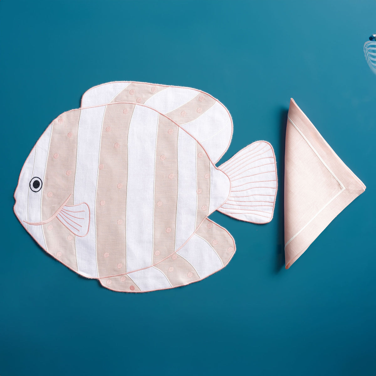 Close-up of embroidered striped fish on white linen