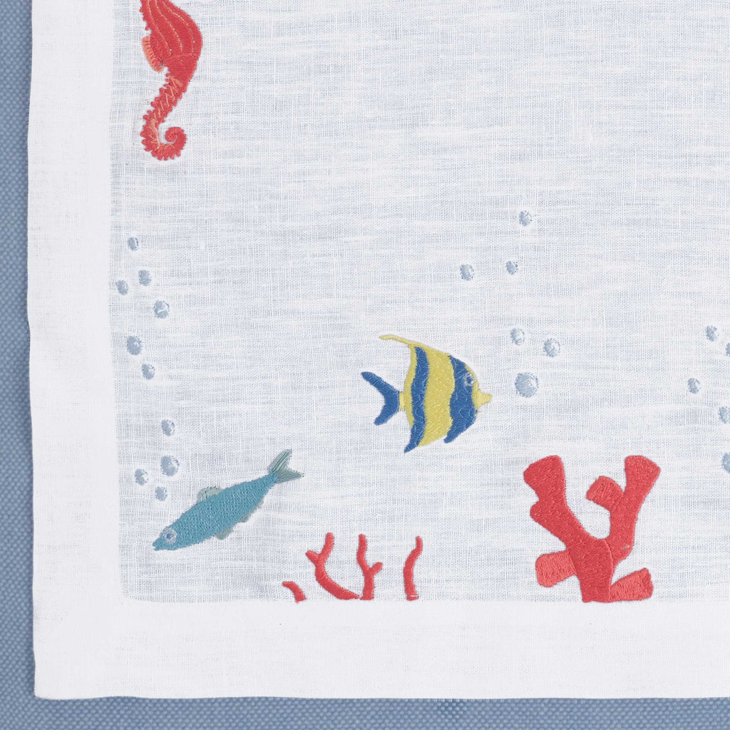 Close-up of embroidered exotic fish on white linen