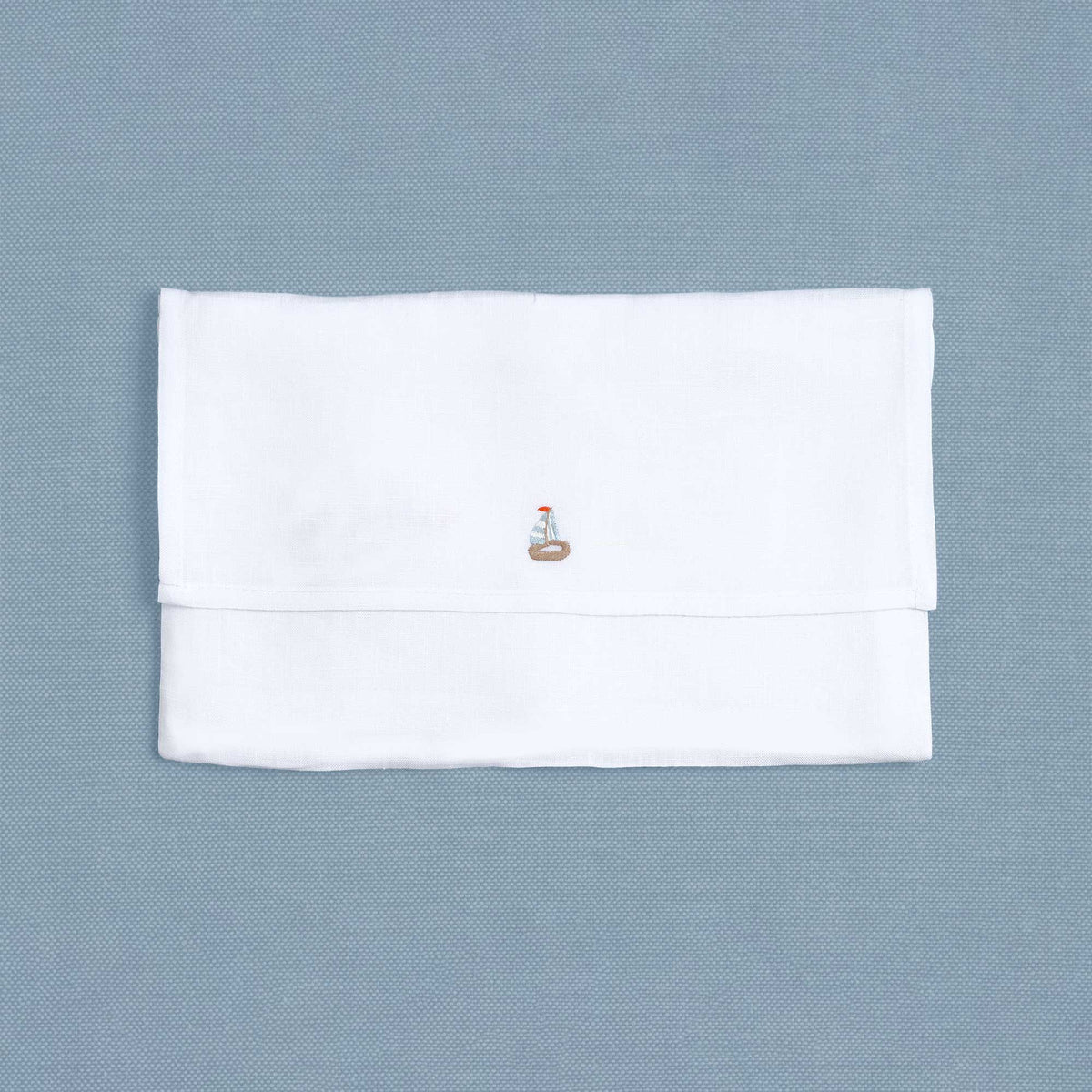 Close-up of embroidered sailboat on white linen cocktail napkin