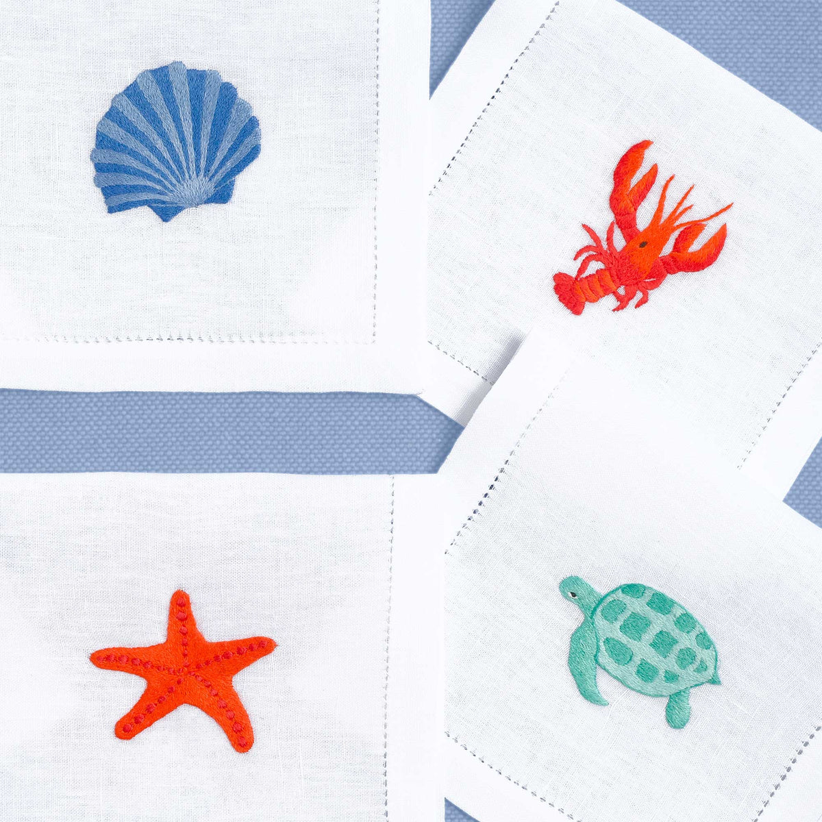 Close-up of embroidered shellfish on white linen cocktail napkin