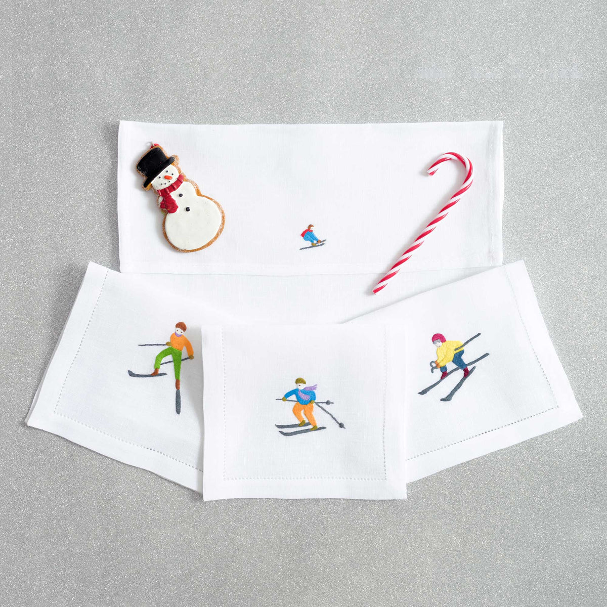 Close-up of embroidered skiers on white linen cocktail napkin