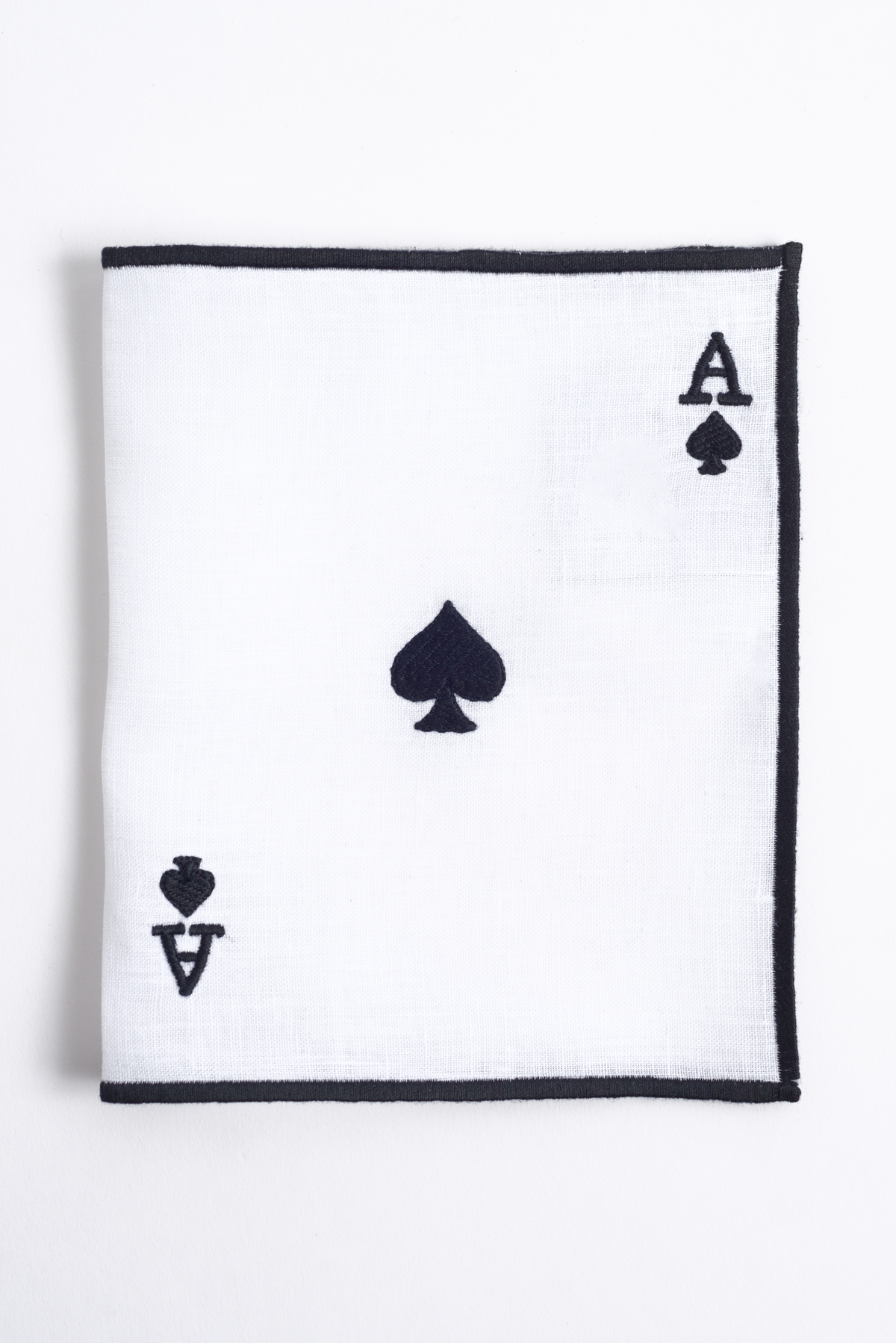 Close-up of embroidered ace on white linen cocktail napkin