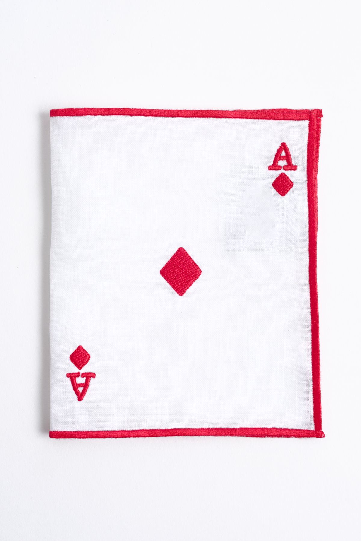 Embroidered playing-card ace detail on white linen cocktail napkin