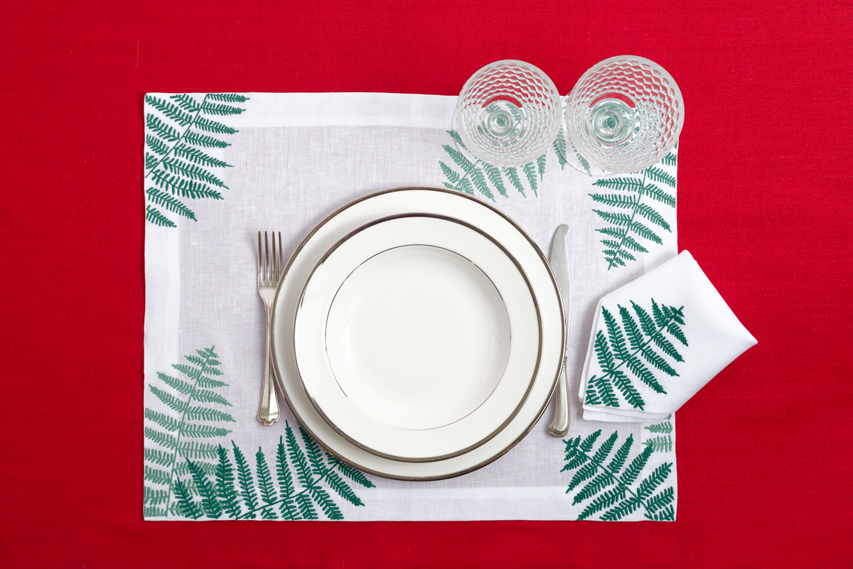 Close-up of embroidered ferns on white linen placemat