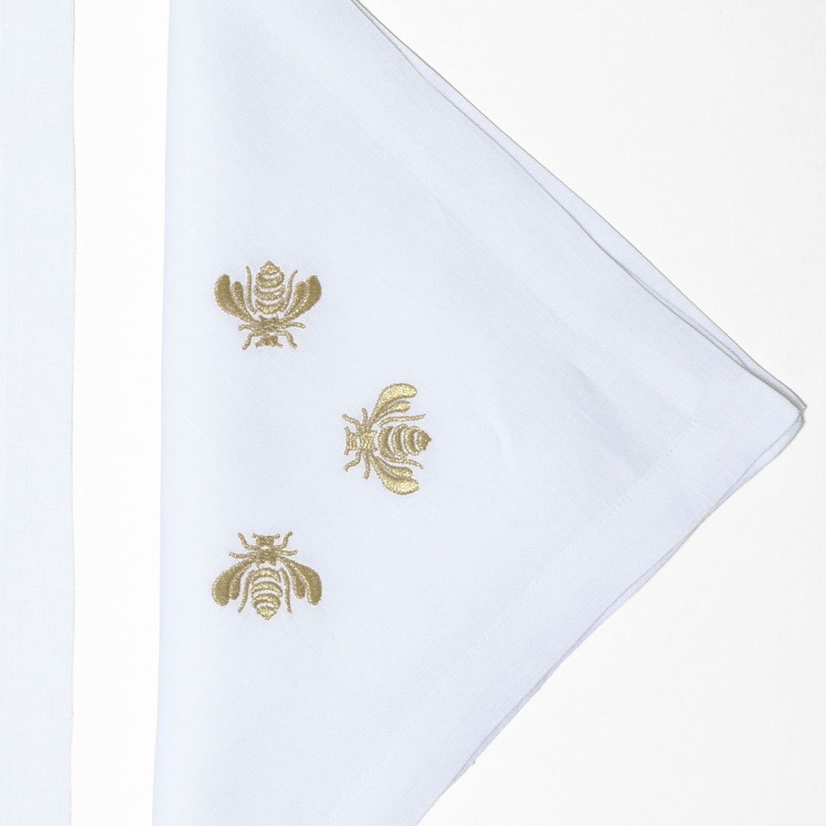 Close-up of golden embroidered bees on white linen