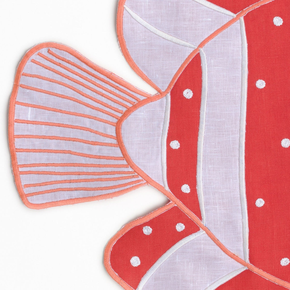 Close-up of embroidered coral fish on white linen