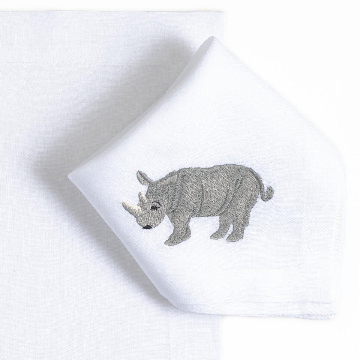 Close-up of embroidered rhinoceros on white linen — Maison Alia